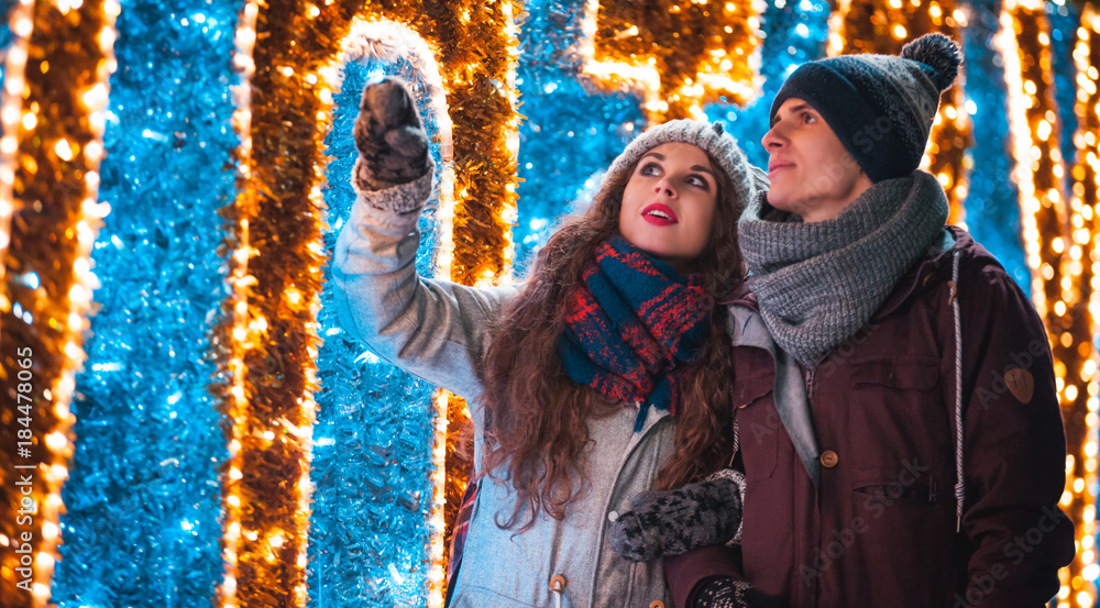 Couple walking near Christmas decoration, lights at the city street