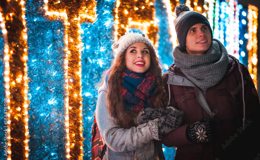 Couple walking near Christmas decoration, lights at the city street