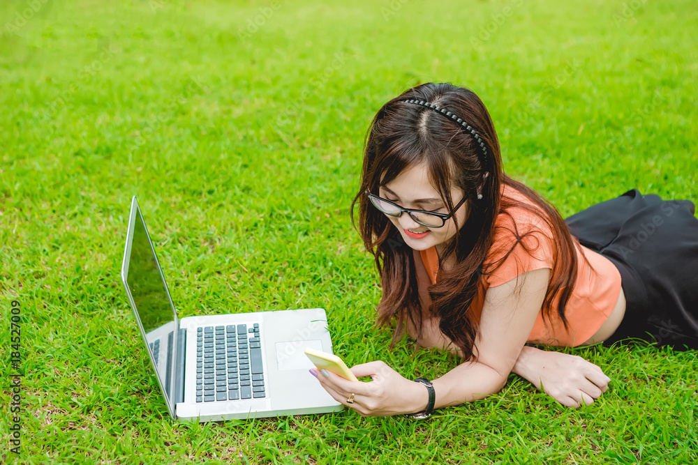 Asian teenage girls sit recreational use of smart phone and laptop computer to use the Internet in t