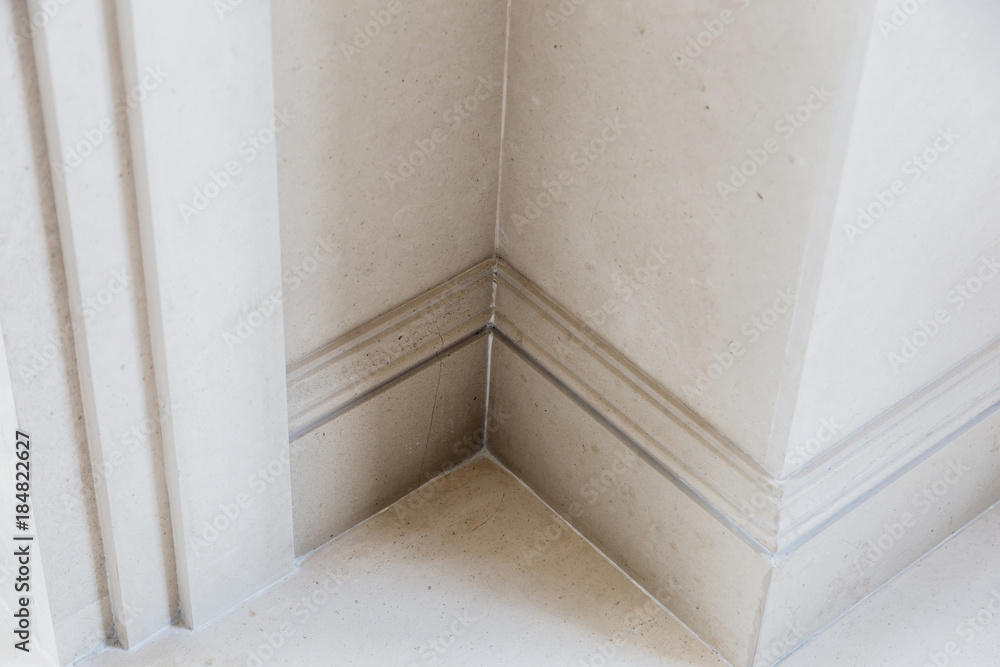 Ornamental moulding in the corner of a white room with dark wood floor interior concept