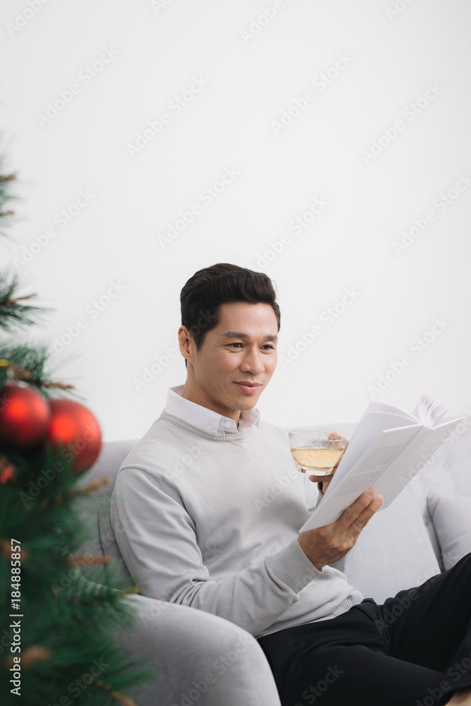 Asian man wearing sweater drinking tea at home during christmas