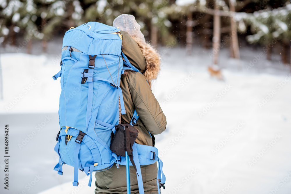 一个穿着冬装的女人背着背包、跟踪棒和保温瓶在雪地里徒步旅行的肖像