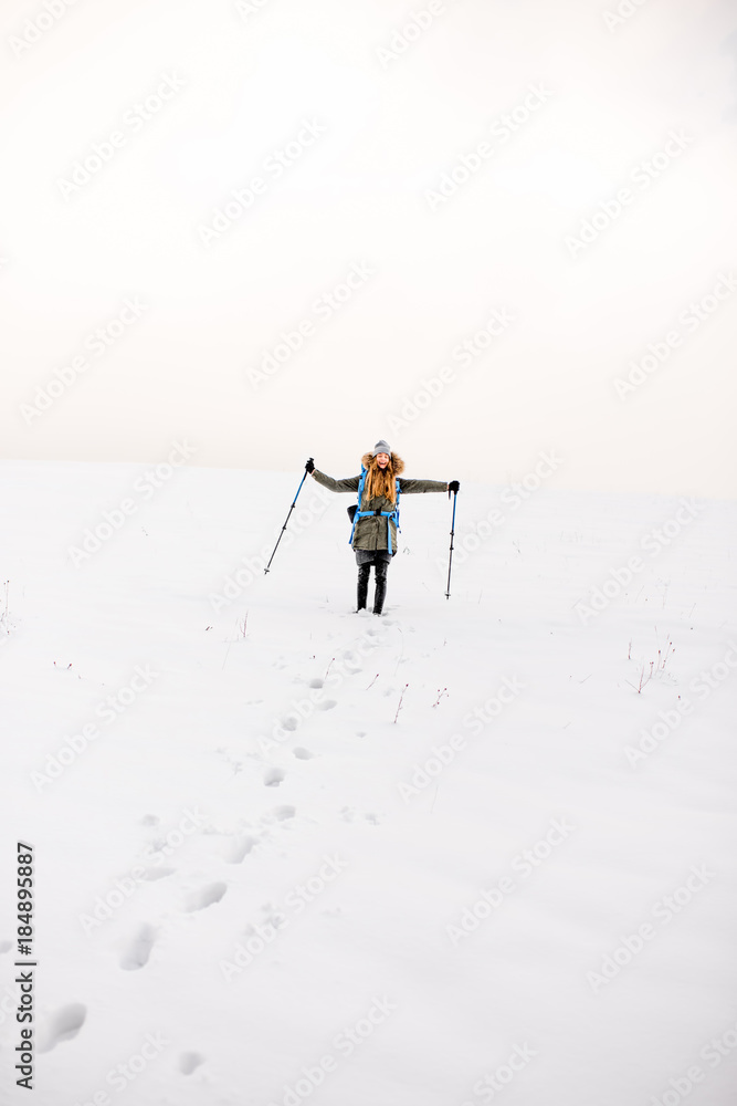 Wide view on the snowy hill with footprints and hiker walking up with backpack in the mountains