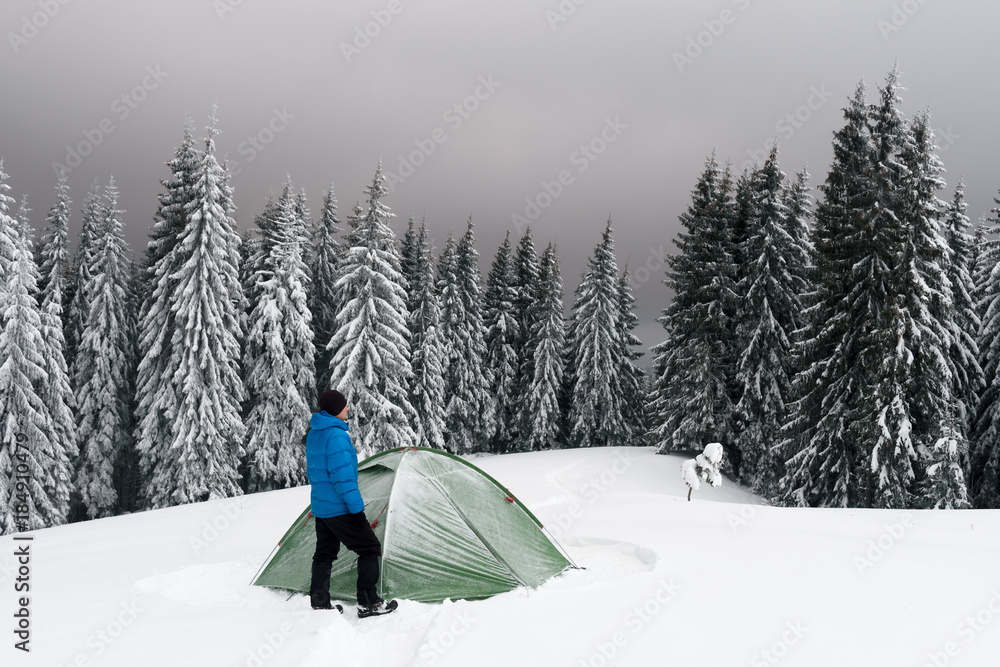 在白雪皑皑的松林背景下，绿色帐篷和游客。令人惊叹的冬季景观。Tou