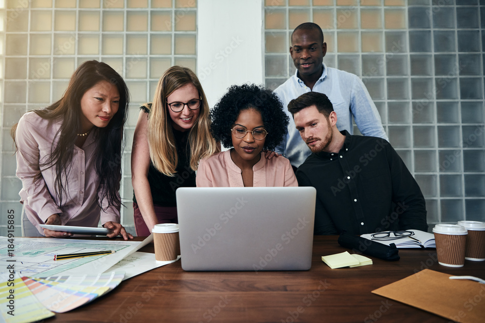 Smiling colleagues working online together in an office