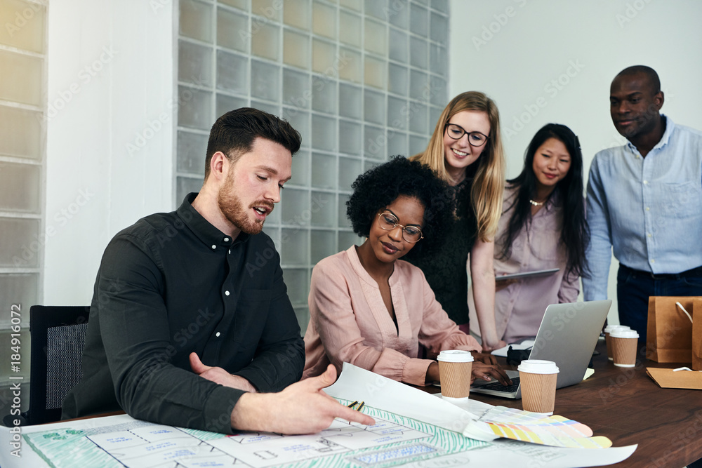 Group of designers discussing blueprints at an office table