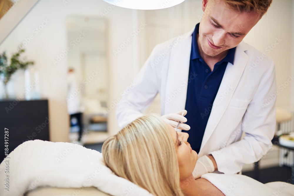 Male doctor doing injections on a mature clients face