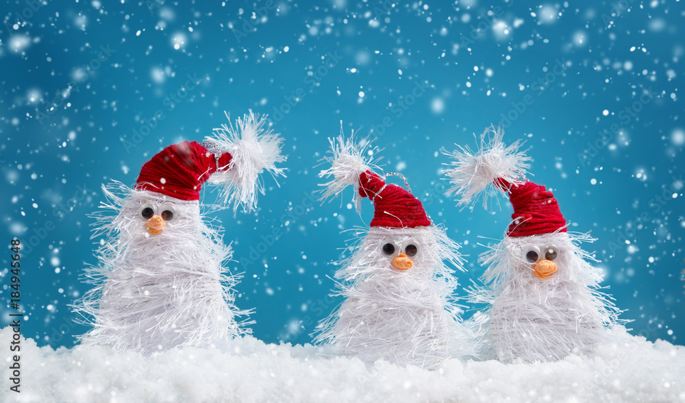 little snowmans on soft snow on blue background