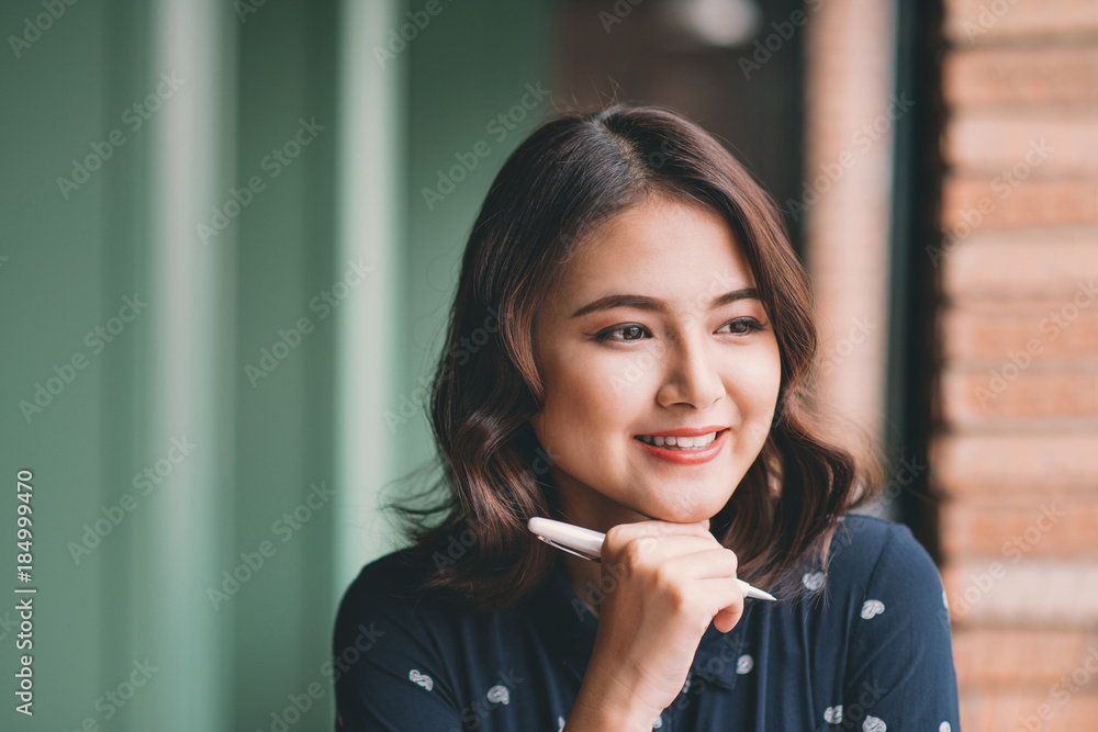 年轻漂亮的女人在靠近窗户的咖啡馆里，一边思考一边写着什么。