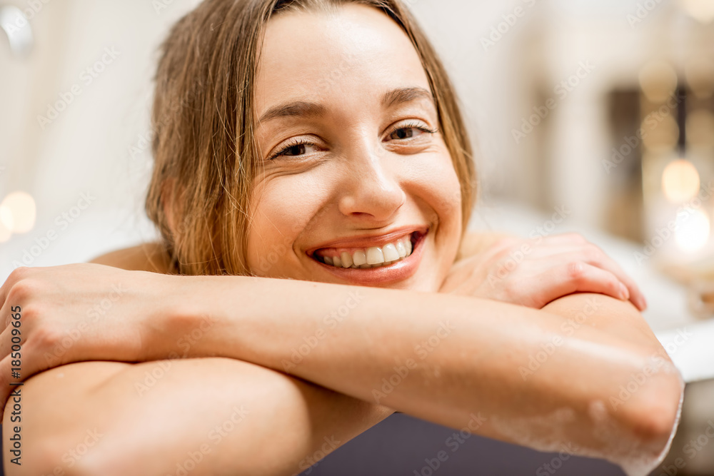 Close-up portrait of a pretty smiling woman lying in the bathroom