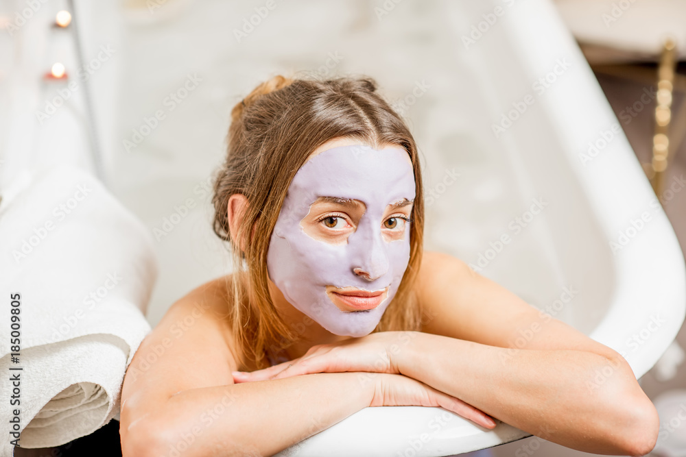 Portrait of a woman in facial mask lying in the retro bath in the bathroom