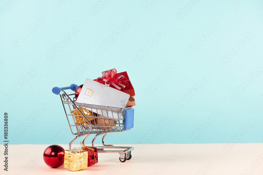 Christmas shopping concept. Shopping cart full with christmas gift boxes and credit card.