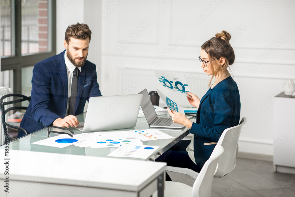 Marketer or analityc manager team dressed in suits working with paper charts and laptops at the whit