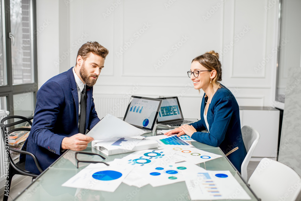 Marketer or analityc manager team dressed in suits working with paper charts and laptops at the whit