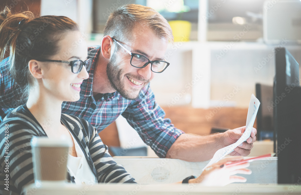 Casual business couple using computer in the office. Two colleagues working together on an innovativ