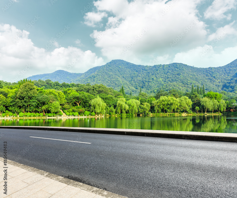 绿色公园里有水的柏油路和山