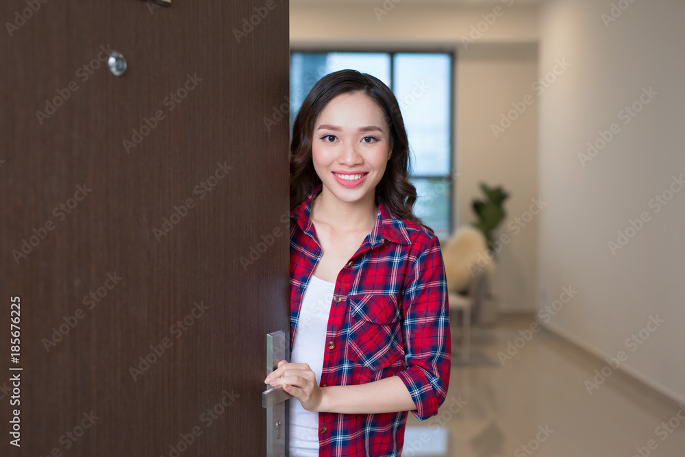 Cheerful asian woman inviting people to enter in home