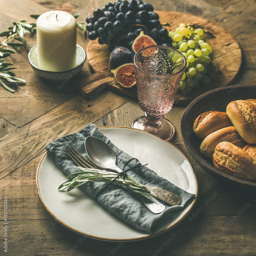 Fall holiday table decoration setting. Plate with napkin, fork, spoon, glass, candle, grapes and fig