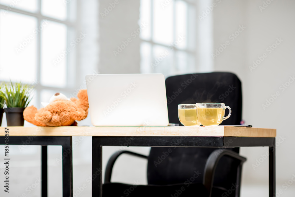 Office table with laptop and tea cups indoors