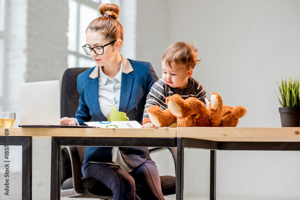 年轻的多任务女商人穿着西装，和他坐在一起处理笔记本电脑和文件