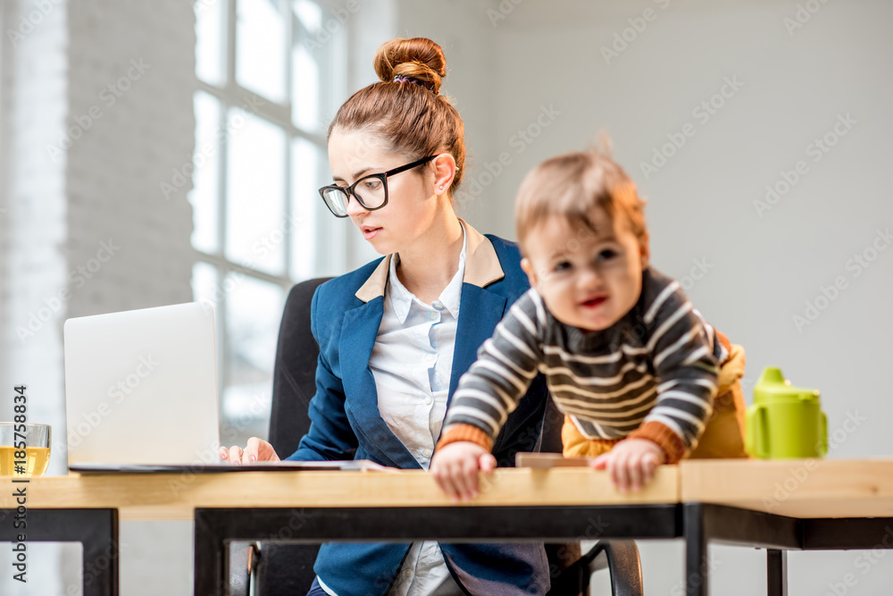 年轻的多任务女商人穿着西装，和他坐在一起处理笔记本电脑和文件