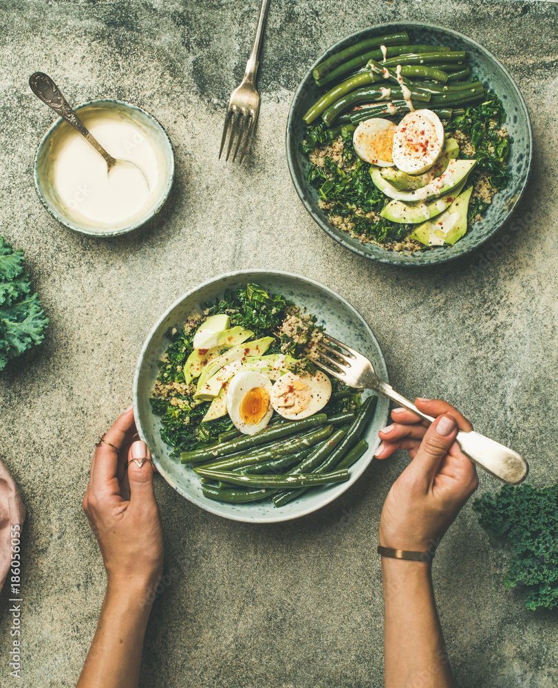 Healthy vegetarian breakfast bowls flat-lay. Quinoa, kale, green beans, avocado, egg and tahini dres