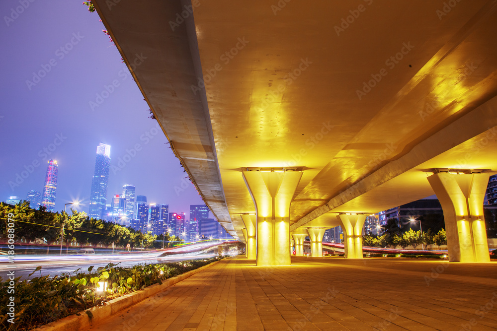 empty sidewalk below elevated road in modern city