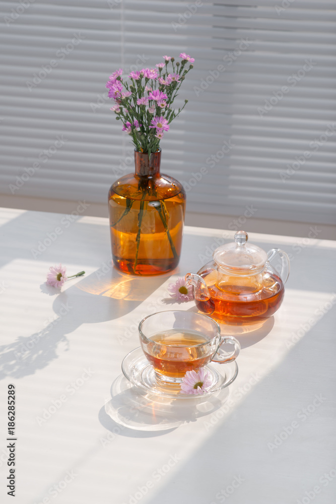 Cup of tea, teapot and vase on the table