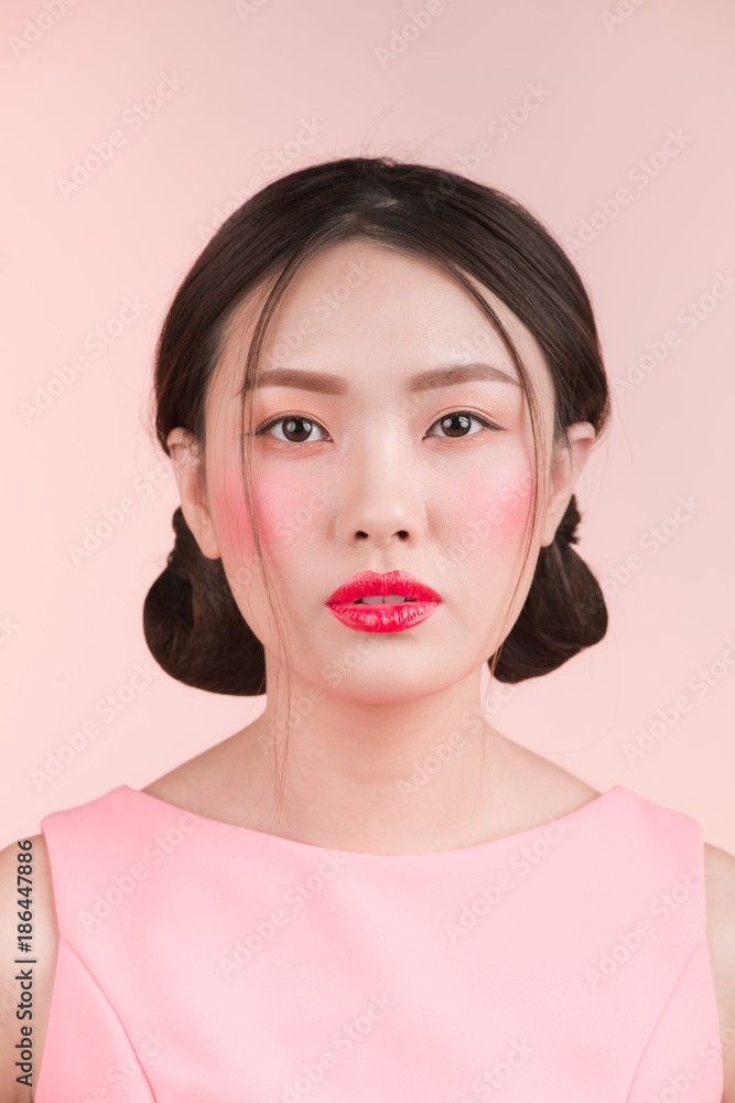 Fashion portrait of a beautiful young woman in a pretty dress over pink background