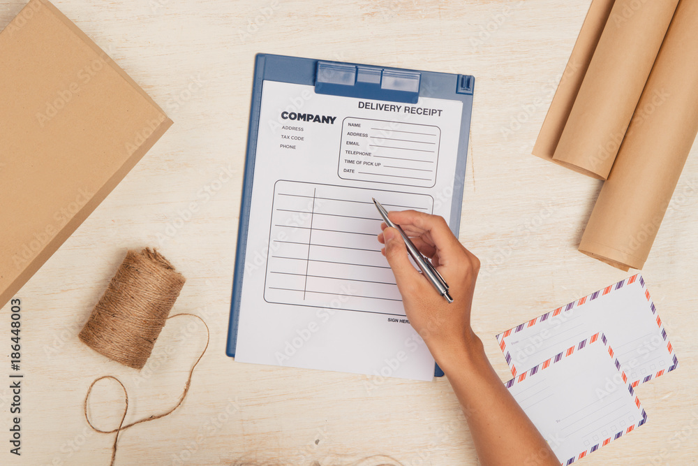 Top view of deliveryman making notes in delivery receipt at table