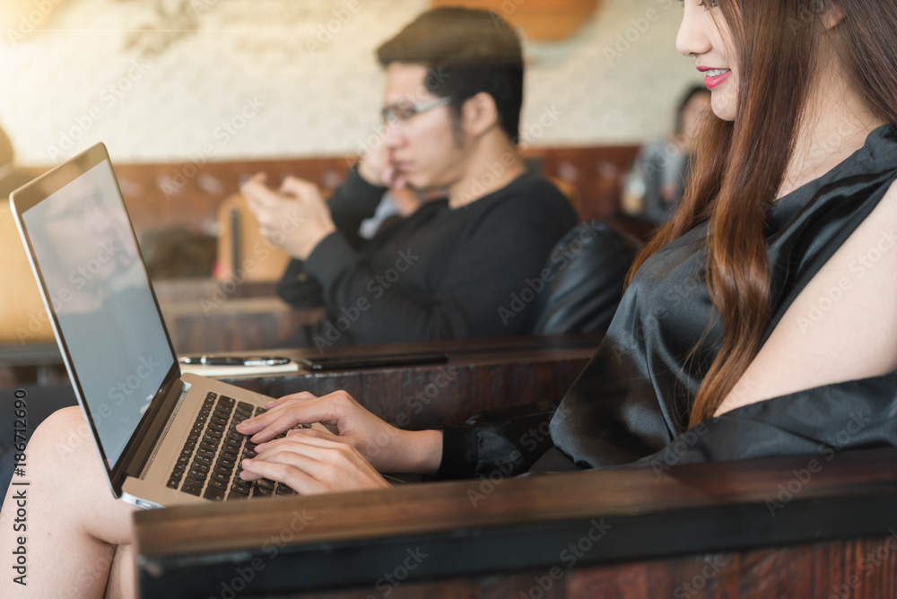 Beautiful asian woman in black dress working with laptop in coffeeshop