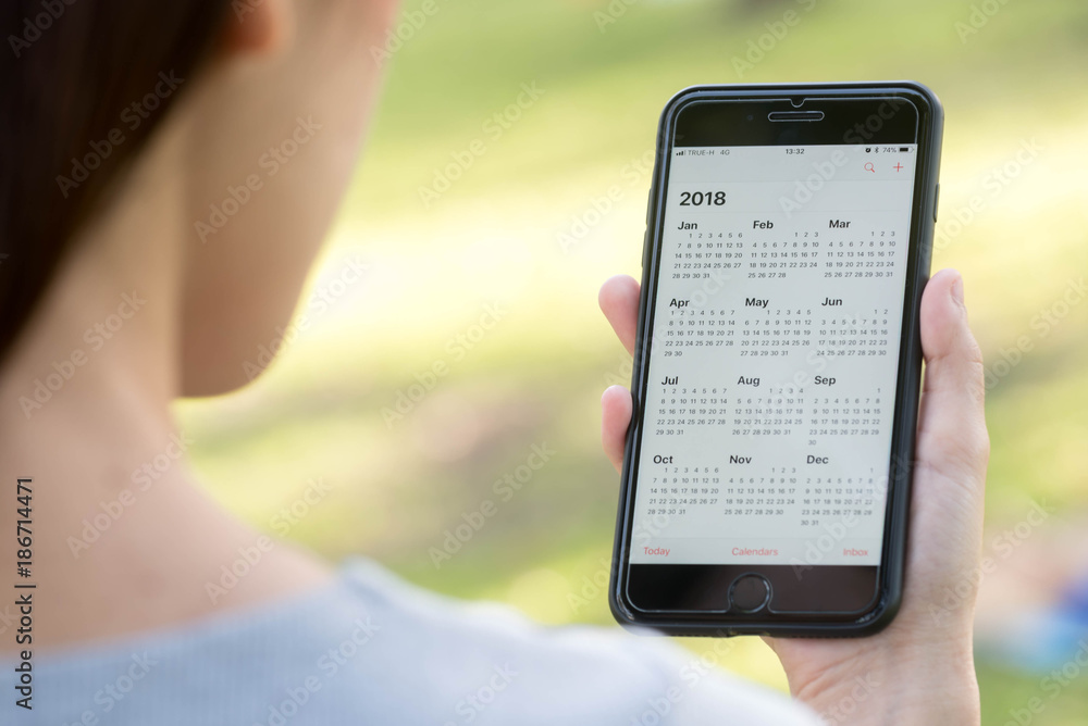 泰国曼谷-2017年11月26日：一位女士手持iphone8加上2018年的节目日历