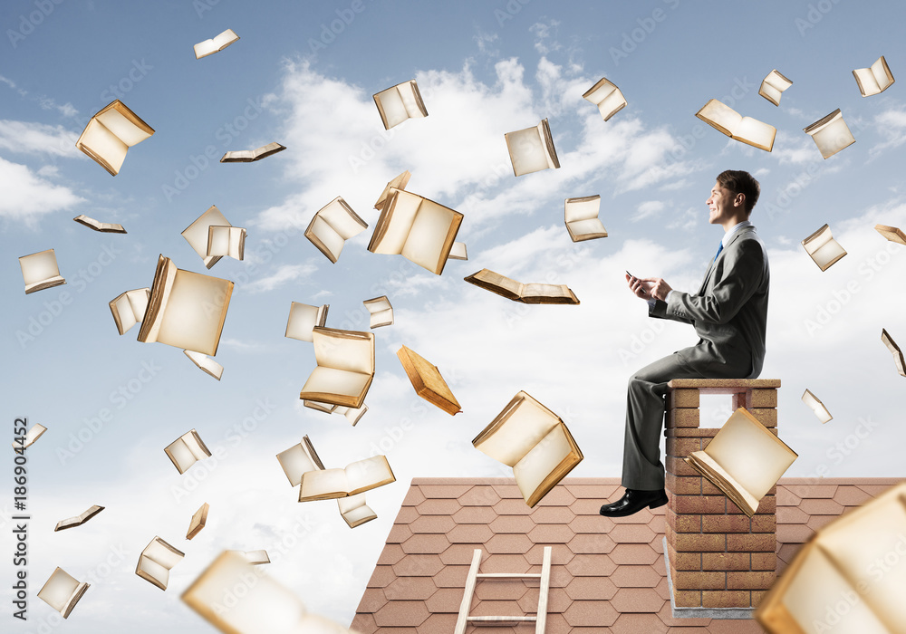 Man using smartphone and many books flying in air