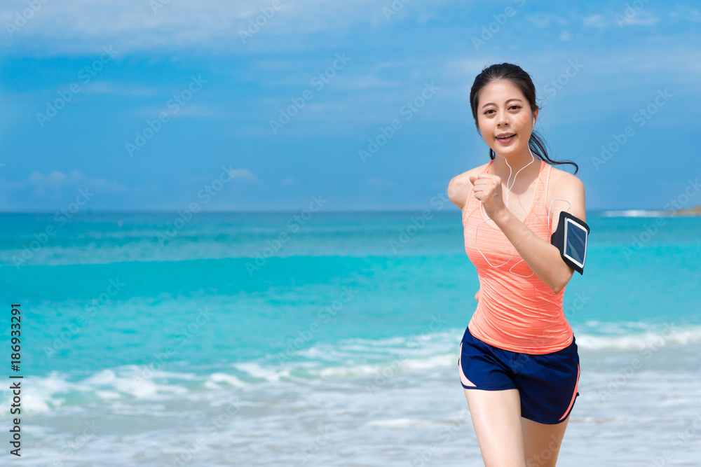 elegant young female jogger running on beach