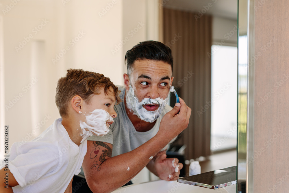 Father and son shaving together in bathroom