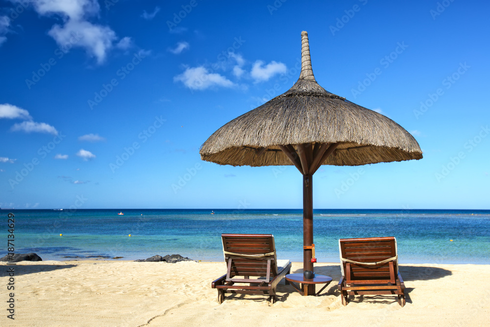 Tropical sand beach and two lounge chairs with sun umbrella