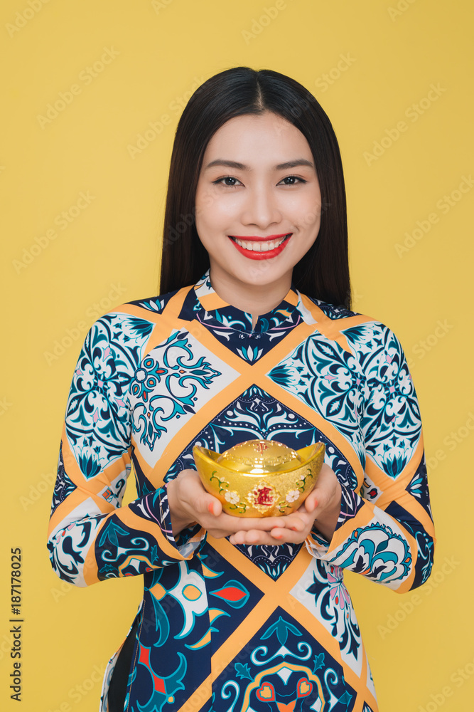 Attractive Vietnamese woman wearing traditional costume, isolated on yellow background