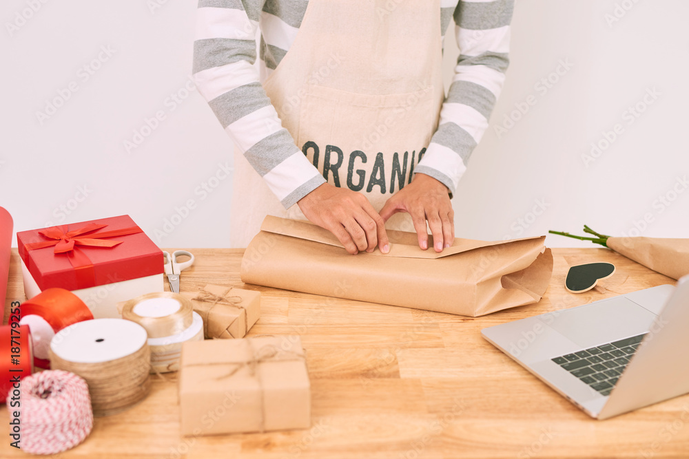 亚洲男子在礼品店工作时包装购物。