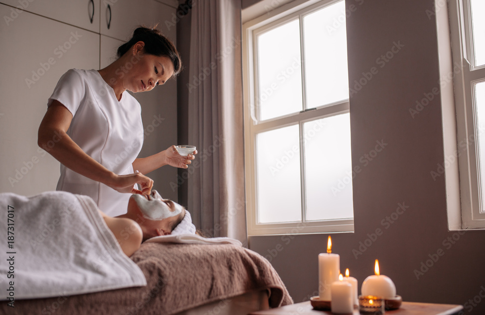 Woman receiving face mask treatment in spa