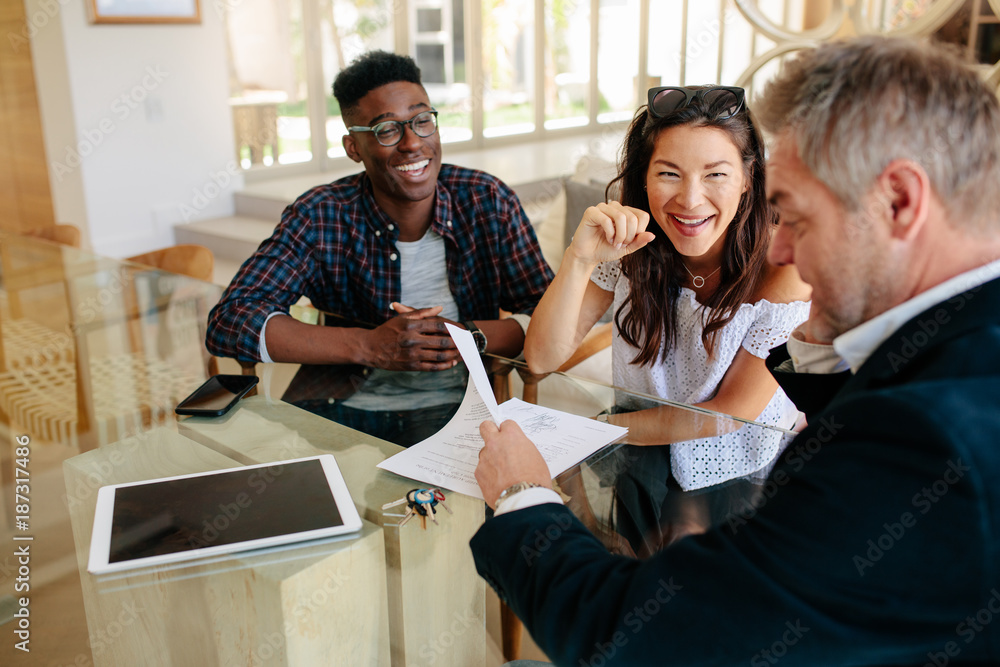 Realtor showing terms of contract to happy couple