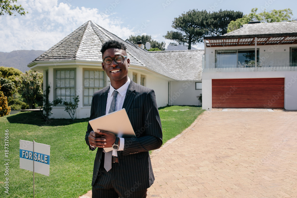 Real estate agent standing outside a house for sale