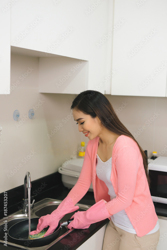 Portrait of attractive young woman cleaning a surface of white kitchen closet