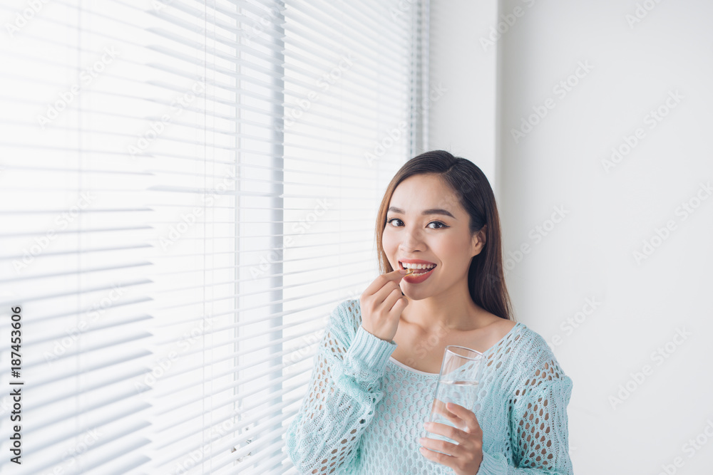 年轻的亚洲美女年轻的女人吃药片和喝水