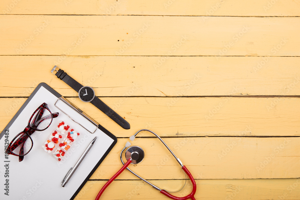 Workplace of doctor - stethoscope and other supplies on the yellow wooden desk