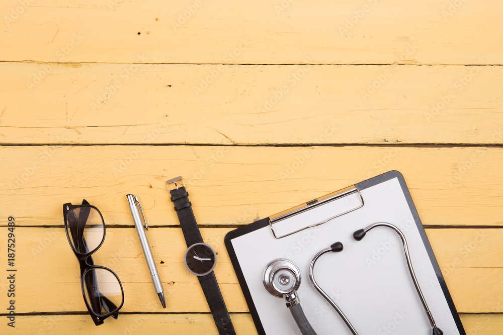 Workplace of doctor - stethoscope and other supplies on the yellow wooden desk