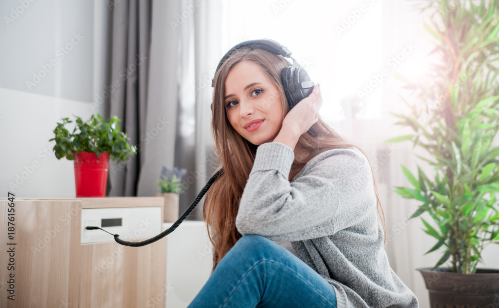 Woman with headphones listening to music at home in living room