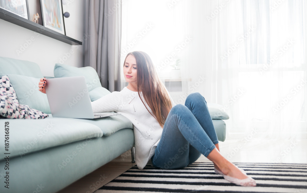 Woman at home using laptop computer on sofa and resting