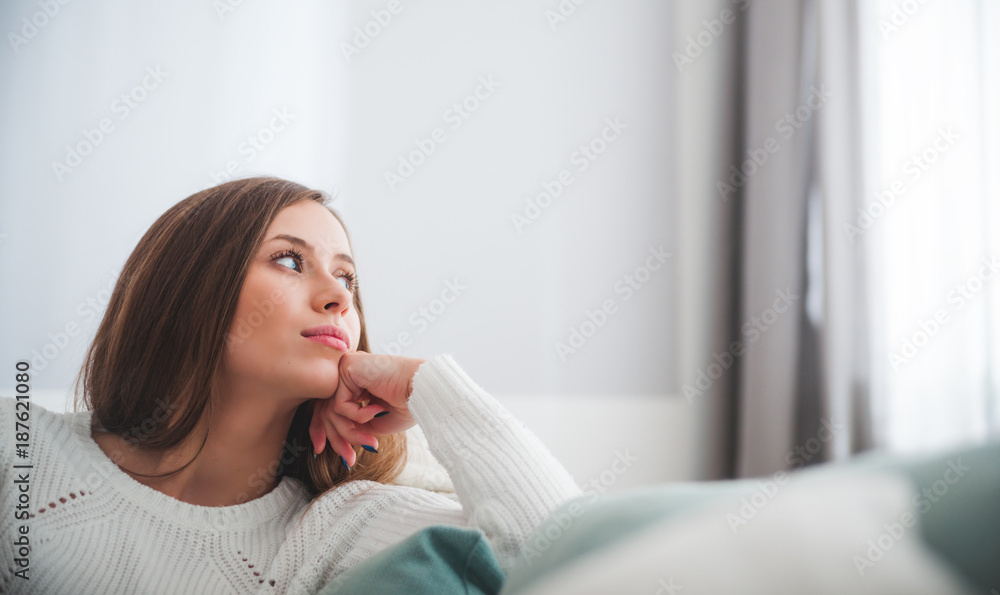 悲伤的女人坐在家里的沙发上沉思，思考概念