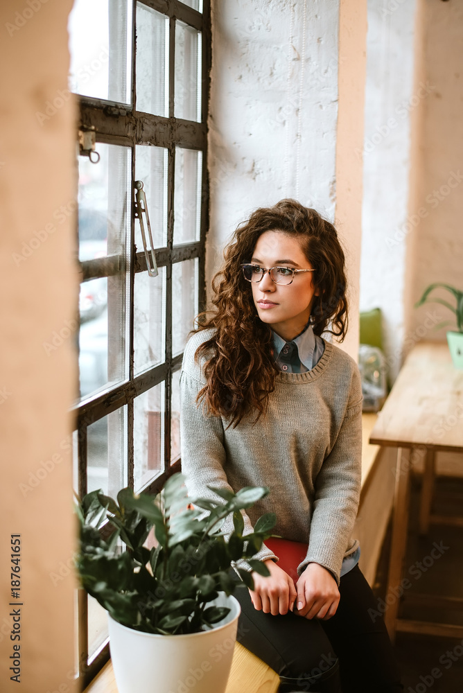 一位体贴迷人的女性透过窗户向外张望的肖像。