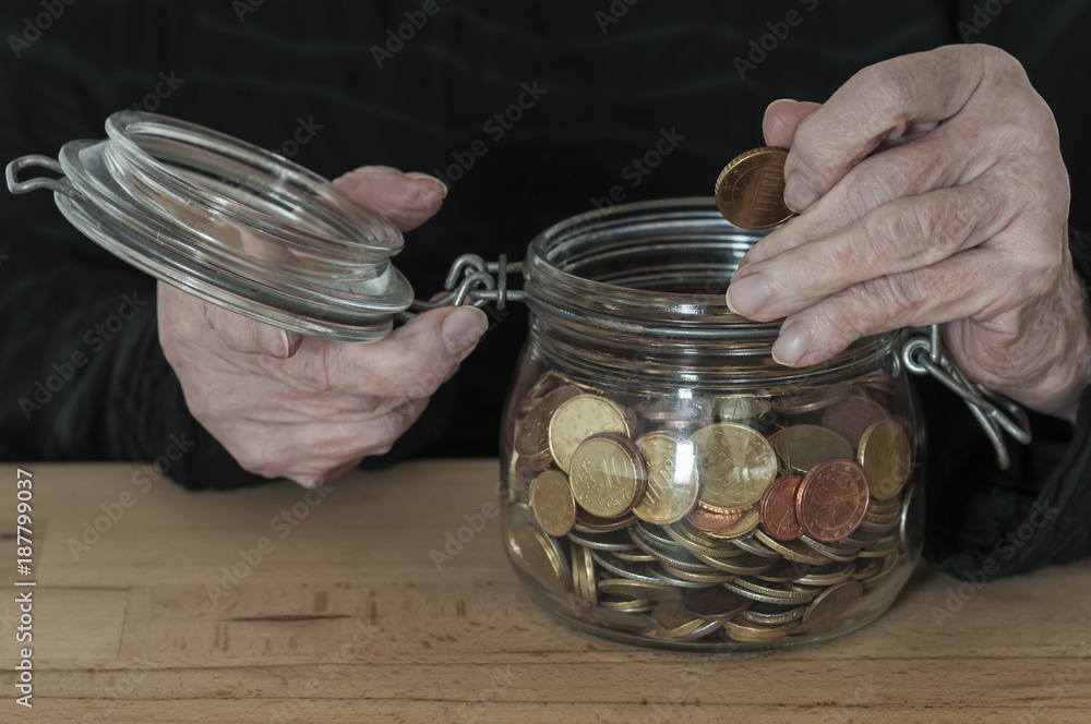 Hands hold a mason jar with small change / Hands of an old woman holding a mason jar with coins.